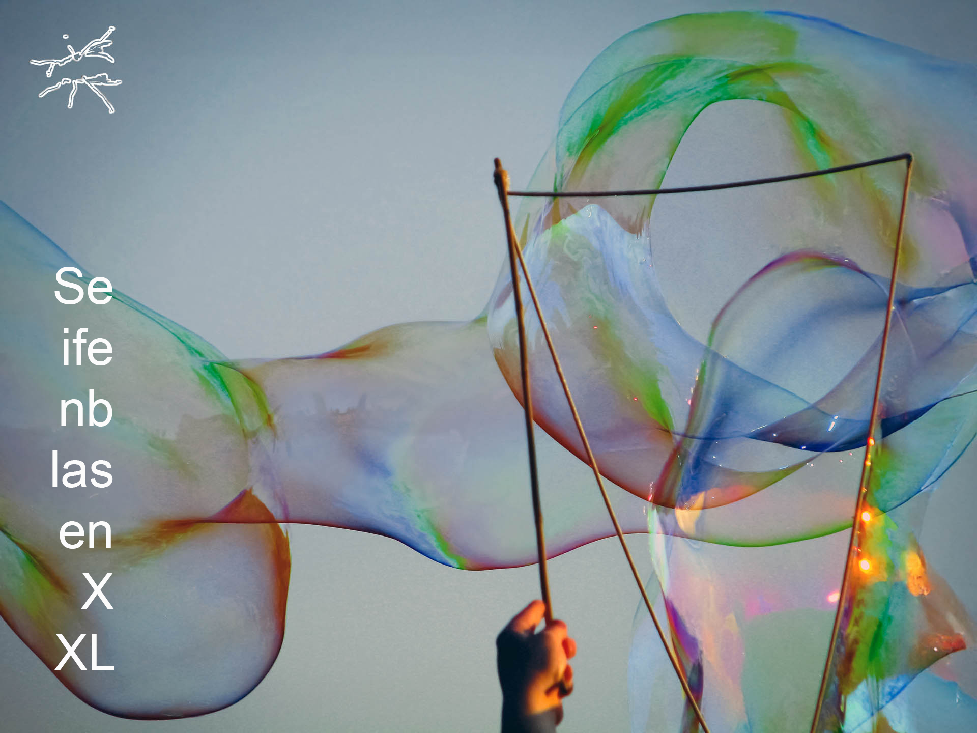 Riesige, schillernde Seifenblasen tanzen in der Luft, gehalten von zwei Stäben mit Schnur, im Licht des frühen Abends.