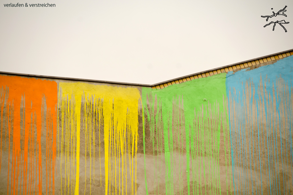 Wandbemalung mit senkrecht verlaufenden Farbspuren in leuchtenden Tönen – flüchtig und rhythmisch zugleich.