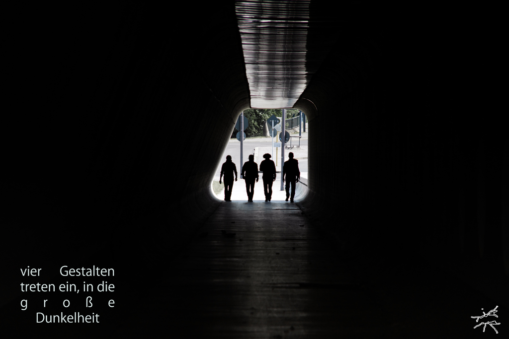 Deutsch:
Ein dunkler Tunnel, dessen Licht am Eingang langsam verblasst. Vier Silhouetten schreiten ruhig in die Tiefe, ihre Schatten verschmelzen mit der Umgebung. Das Licht hinter ihnen flackert, während sich vor ihnen nur Dunkelheit erstreckt.
English:
A dark tunnel where light fades at the entrance. Four silhouettes walk calmly into the depths, their shadows blending with the surroundings. The light behind them flickers as only darkness unfolds ahead.