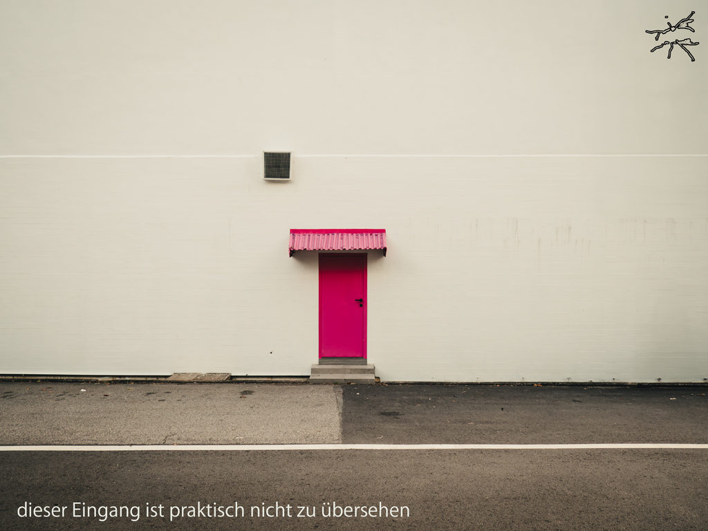 Pinke Tür in heller Wand, minimaler Eingang vor Asphaltfläche.