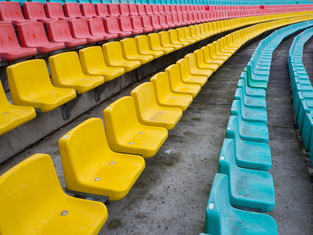 Deutsch:
Eine Reihe bunter Stadion-Sitze in Gelb, Rot und Türkis. Die Perspektive führt den Blick entlang der geschwungenen Linien, eine Struktur aus Wiederholung und Rhythmus. Leere Plätze, die auf Bewegung warten, auf Menschen, auf Geschichten.
English:
A row of colorful stadium seats in yellow, red, and turquoise. The perspective guides the eye along the curved lines, a structure of repetition and rhythm. Empty seats waiting for movement, for people, for stories.