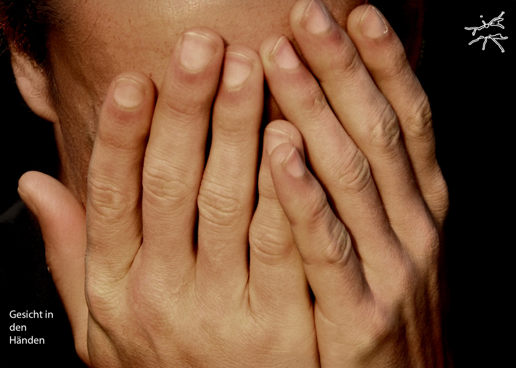 Deutsch: Ein Mann sitzt mit gesenktem Kopf, sein Gesicht verborgen in seinen langen, schmalen Händen. Die Finger spannen sich, als hielten sie eine unsichtbare Last. Die Stille im Raum verstärkt das Gefühl von Schwere und Suche nach Halt. English: A man sits with his head lowered, his face hidden in his long, slender hands. His fingers tense as if holding an invisible weight. The silence in the room amplifies the sense of heaviness and the search for stability.