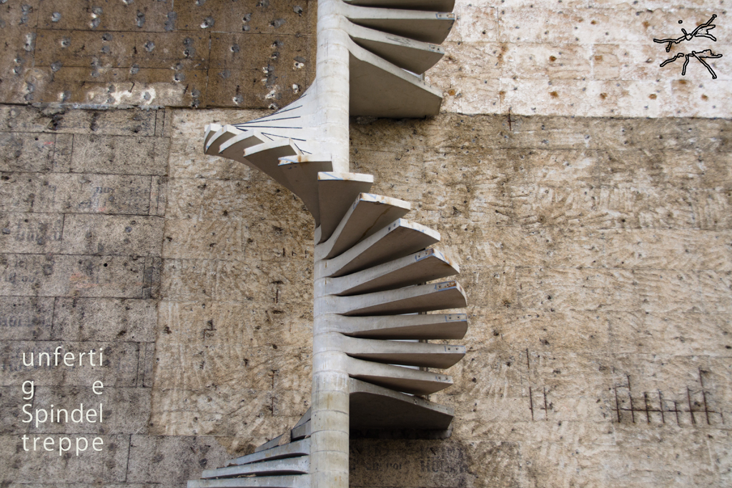 Unvollendete Betontreppe an roh belassener Wand, spiralförmig und abrupt endend – Symbol für Unterbrechung und Fragilität.
