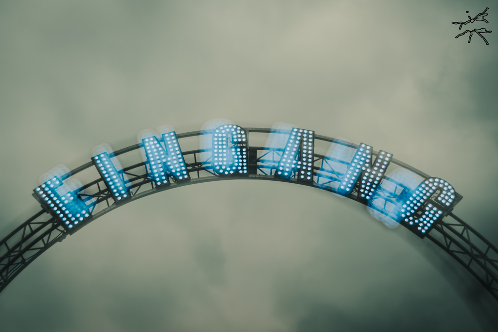 271970 Leuchtendes „Eingang“-Schild vor wolkenverhangenem Himmel, leicht verschwommen, stimmungsvoll und entrückt.