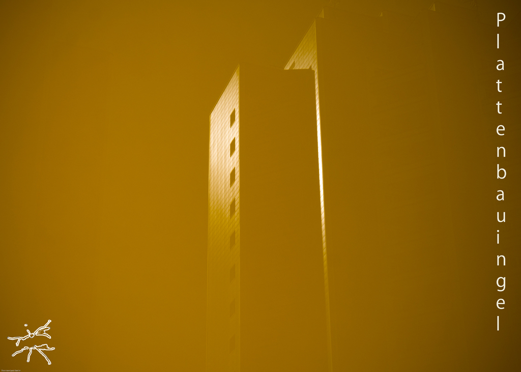 Abstrakte, monochrome Fotografie eines Plattenbau-Hochhauses, in Gelb getaucht, mit dem vertikalen Text "Plattenbau in gelb". Abstract, monochrome photograph of a high-rise panel building, dipped in yellow, with the vertical text "Plattenbau in gelb".