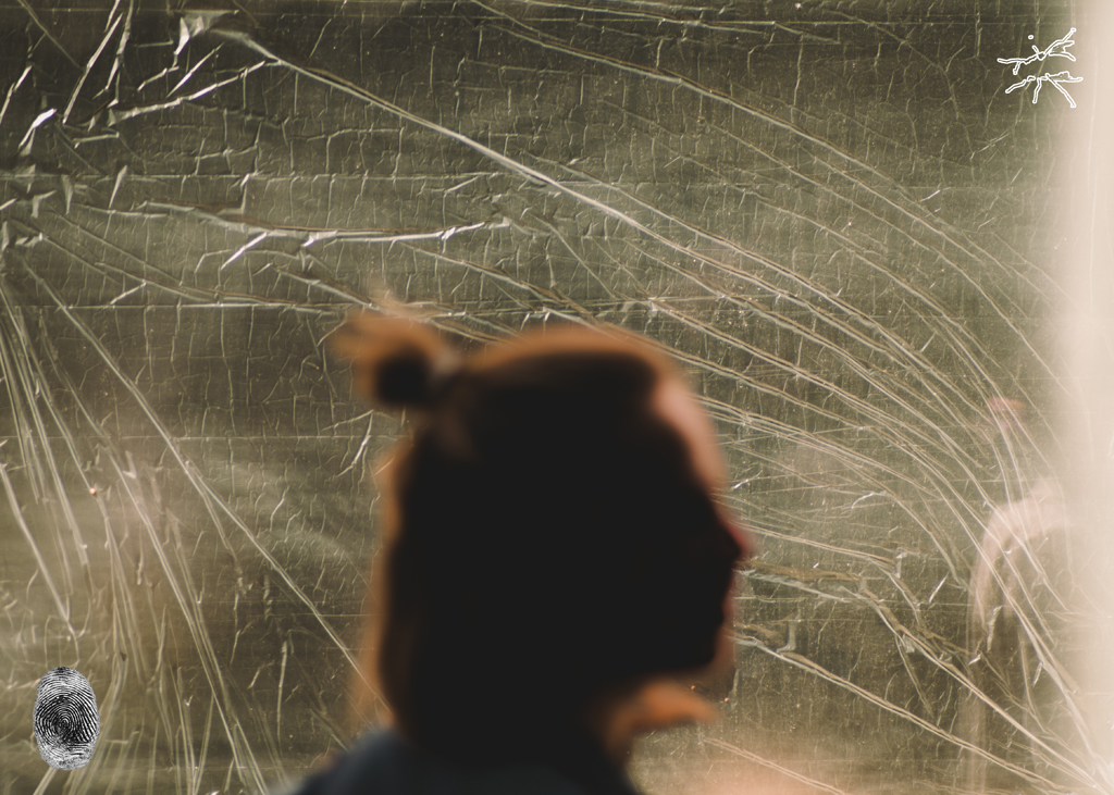 Verschattete Silhouette einer Person vor zerknitterter, lichtdurchbrochener Folie; vorn ein digitaler Fingerabdruck, oben rechts das Fliegen-Symbol.