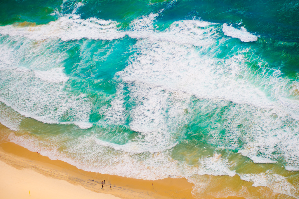 Luftaufnahme von Meereswellen, die auf einen sandigen Strand treffen